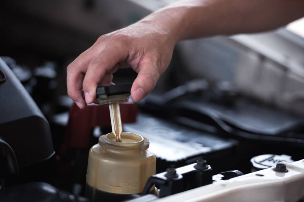 Man hand open power steering cap up for checking level of power steering fluid in the system, car maintenance service concept.