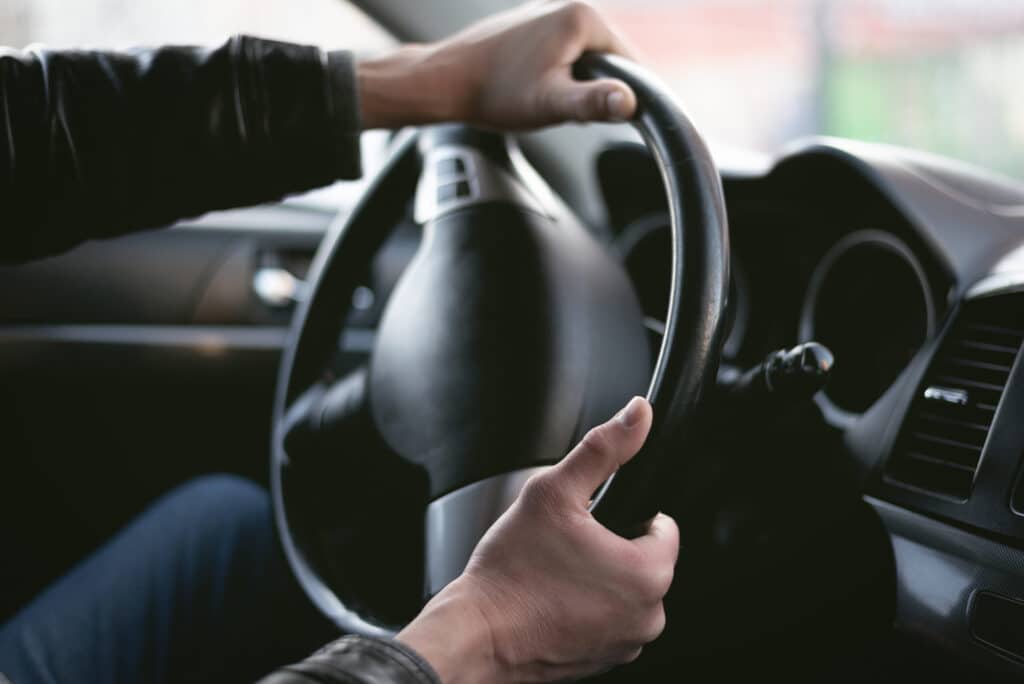 Cropped image of hands turning a steering wheel