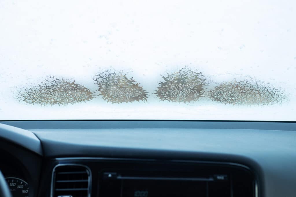 frozen car windshield in winter, inside the car, cold temperature, melting ice on the window, working climate control. Close-up photo with copy space